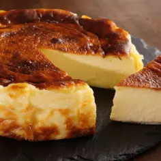 Pyszny, lekko przypieczony sernik na czarnej desce. Jeden kawałek już został odkrojony, idealny na deser. Sernik kcal.