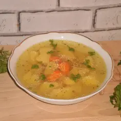 Aromaticzny rosół z ziemniakami i marchewką, ozdobiony natką pietruszki. Idealny na chłodne dni.
