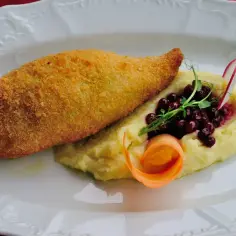 Złocisty dewolaj z chrupiącą panierką, podany z kremowym purée, borówkami i ozdobiony marchewką.