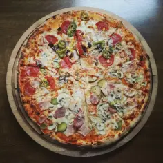 Apetyczna pizza 30 cm z różnymi dodatkami: salami, pieczarki, kukurydza, jalapeno, ogórek kiszony. Zastanawiasz się, ile kalorii ma pizza 30 cm?