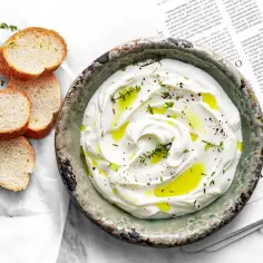Labneh co to? Kremowy, gęsty serek, polany oliwą i posypany ziołami, podany z chrupiącym pieczywem.
