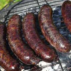 Kaszanka, tradycyjna polska kiełbasa, piecze się na grillu. Jej ciemny kolor i charakterystyczna faktura świadczą o tym, z czego jest kaszanka: z krwi i podrobów.