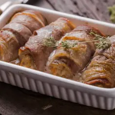 Roladki schabowe pieczone w naczyniu, zawinięte w boczek, z gałązkami tymianku.