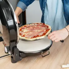 Osoba wkłada pizzę z szynką do pieca. Zobacz, ile piec pizze w kilka minut!