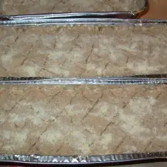 Gotowe do pieczenia pasztety w foremkach aluminiowych, posypane bułką tartą. Idealne, by dowiedzieć się, jak piec pasztet w foremkach aluminiowych.