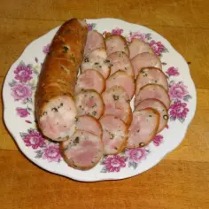 Kiełbasa drwala pokrojona w plastry na talerzu z kwiatowym wzorem. Idealna na grilla, oto jak zrobić kiełbasę drwala!