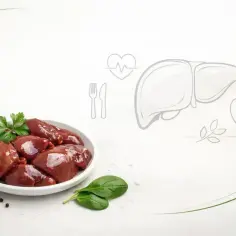 Surowa wątróbka na talerzu, obok czosnek i szpinak. Grafika wątroby i serca sugeruje, czy wątróbka jest zdrowa.
