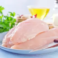 Na talerzu surowe piersi kurczaka, obok natka pietruszki, oliwa i sól. Zastanawiasz się, ile waży pierś z kurczaka?
