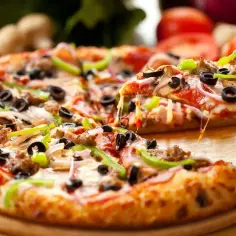Pyszna pizza z mięsem, oliwkami i papryką, idealna na **dzień pizzy**. Ser ciągnie się apetycznie, gdy podnosimy kawałek.