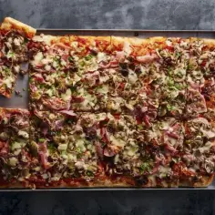 Najlepsza pizza domowa na dużą blachę, obficie posypana szynką, pieczarkami i oliwkami. Idealna na rodzinne spotkanie.