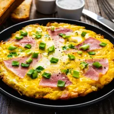 Pyszny omlet z szynką i serem, posypany szczypiorkiem, idealny na śniadanie. Dowiedz się, jak zrobić omlet z szynką i serem!