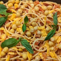 Spaghetti z ciecierzycą, startym serem i listkami bazylii.