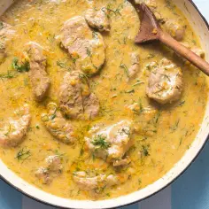 Bitki wieprzowe w sosie własnym z cebulką i koperkiem, podane w białej patelni, gotowe do podania.