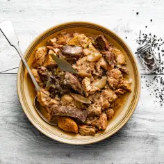 Pyszna, aromatyczna świeżonka duszona z cebulką i przyprawami, gotowa do podania. Obok solniczka z pieprzem.
