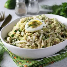Lekka sałatka z tuńczykiem, jajkiem i ogórkiem, udekorowana koperkiem. Idealna na szybki lunch.