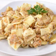 Pyszne lazanki z mięsem mielonym i warzywami, udekorowane gałązką natki pietruszki.
