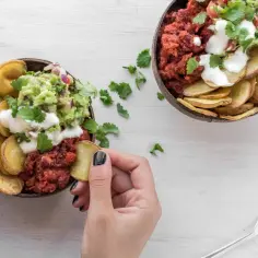 Dwie miski z pysznym daniem: pieczone ziemniaki, guacamole, fasola i śmietana. Ziemniaki wartości odżywcze w zdrowym posiłku.