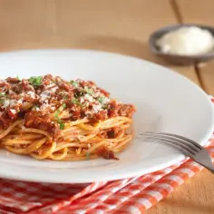 Pyszne spaghetti z mięsem mielonym, posypane parmezanem. Idealne na obiad, gdy chcesz wiedzieć, ile spaghetti z mięsem mielonym kcal zjesz.