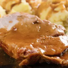 Mięciutka karkówka w sosie, podana z purée ziemniaczanym. Danie wygląda apetycznie i sycąco.