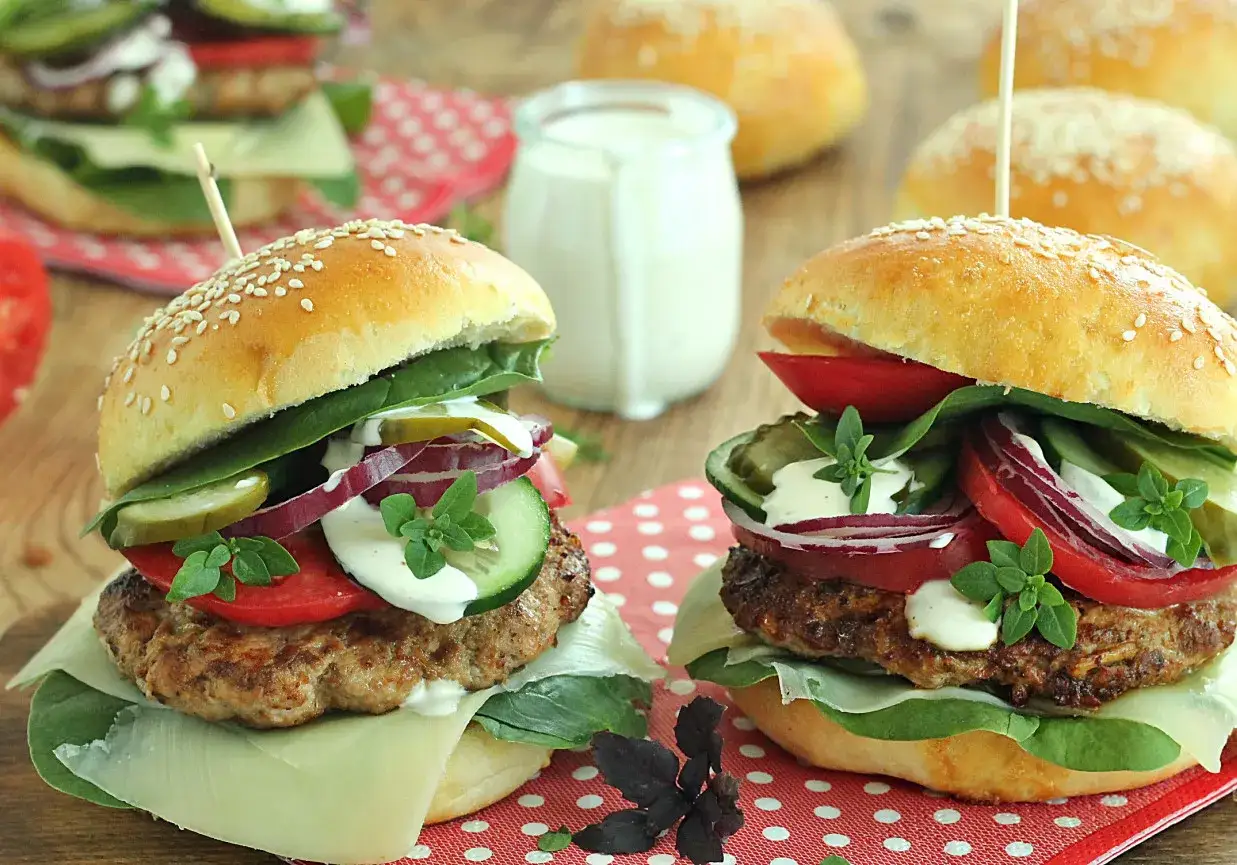 Dwa soczyste burgery z serem, pomidorem, ogórkiem, cebulą i sałatą. Idealne, by pokazać, jak zrobić hamburgera.