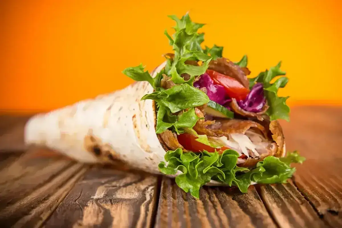 Pyszny kebab zawinięty w tortillę, pełen mięsa, warzyw i sosu. Idealny na szybki posiłek, choć warto pamiętać o jego kcal.