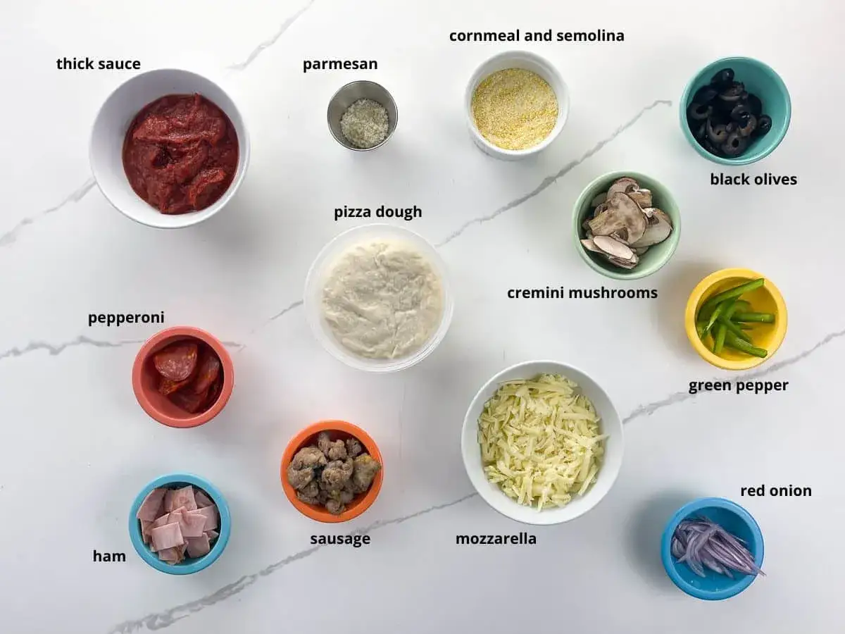 Wszystkie potrzebne dodatki do pizzy: sos, ser, pepperoni, szynka, kiełbasa, pieczarki, oliwki, papryka, cebula, mąka kukurydziana i semolina.