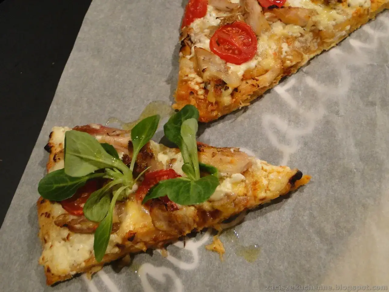 Dwie porcje pysznej pizzy z twarogu, pomidorkami i kurczakiem, udekorowane świeżą sałatką.