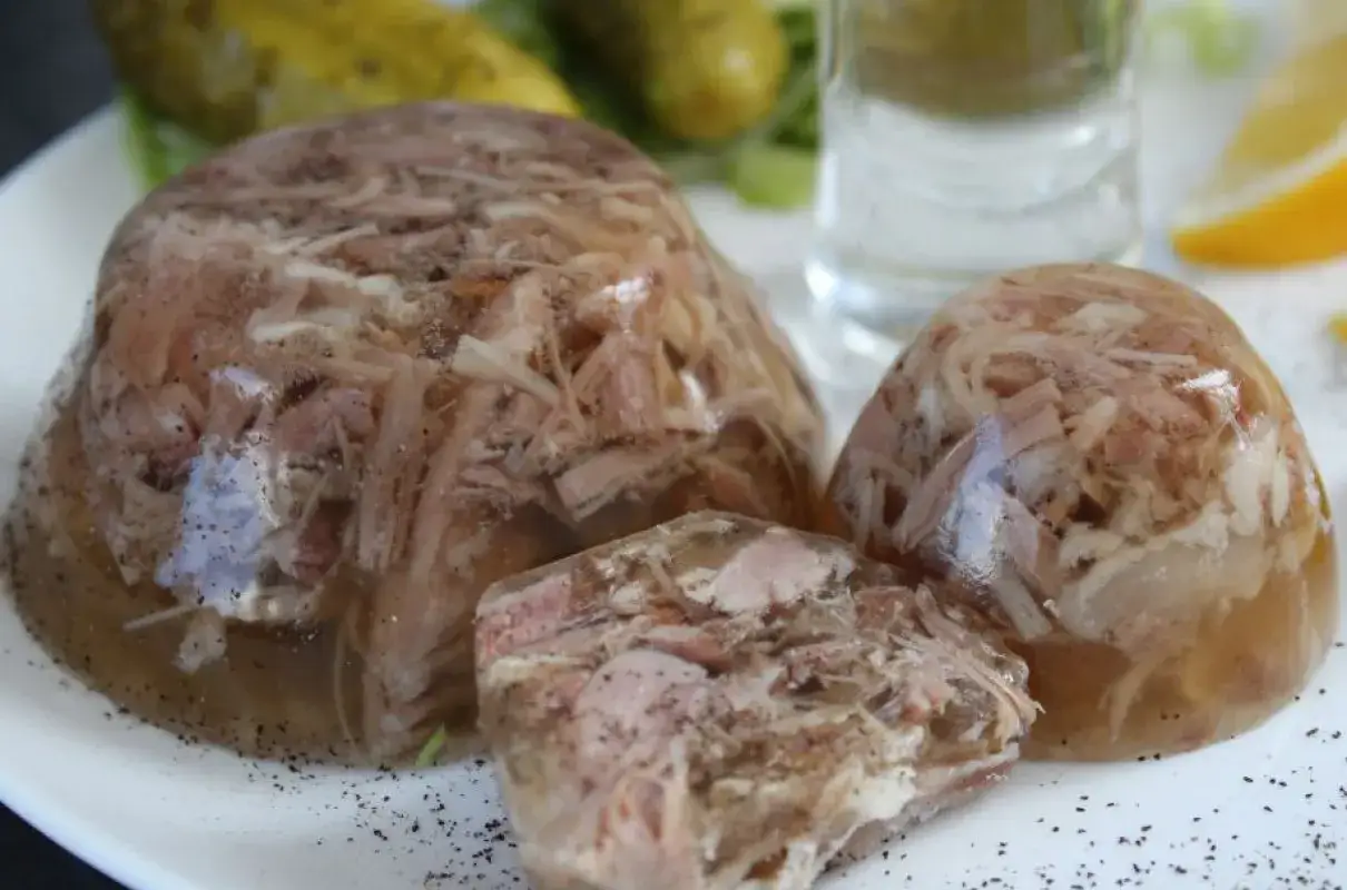 Tradycyjna galareta wieprzowa, podana z ogórkami kiszonymi i kieliszkiem wódki. Pyszne danie, które smakuje jak u babci.
