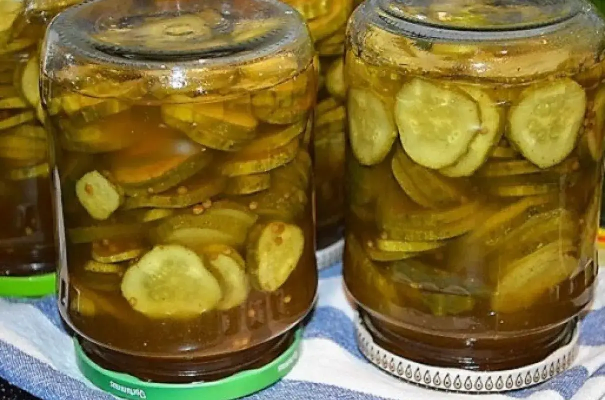 Słoiki z ogórkami w curry ze skórką, gotowe do spiżarni. Aromatyczne plastry ogórków w zalewie.