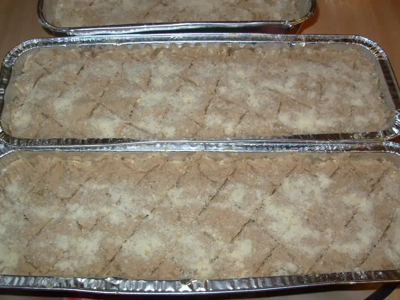 Gotowe do pieczenia pasztety w foremkach aluminiowych, posypane bułką tartą. Idealne, by dowiedzieć się, jak piec pasztet w foremkach aluminiowych.