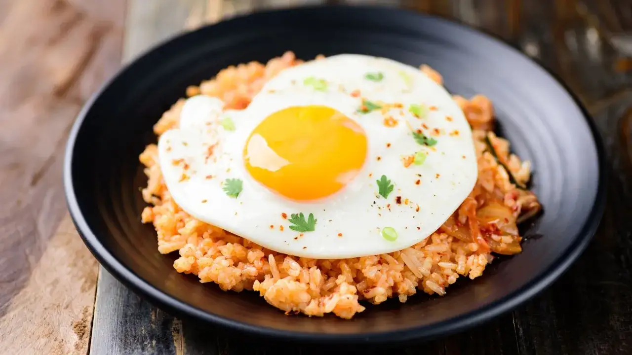 Pyszny obiad z jajek na ryżu z kimchi, posypany szczypiorkiem i płatkami chili.