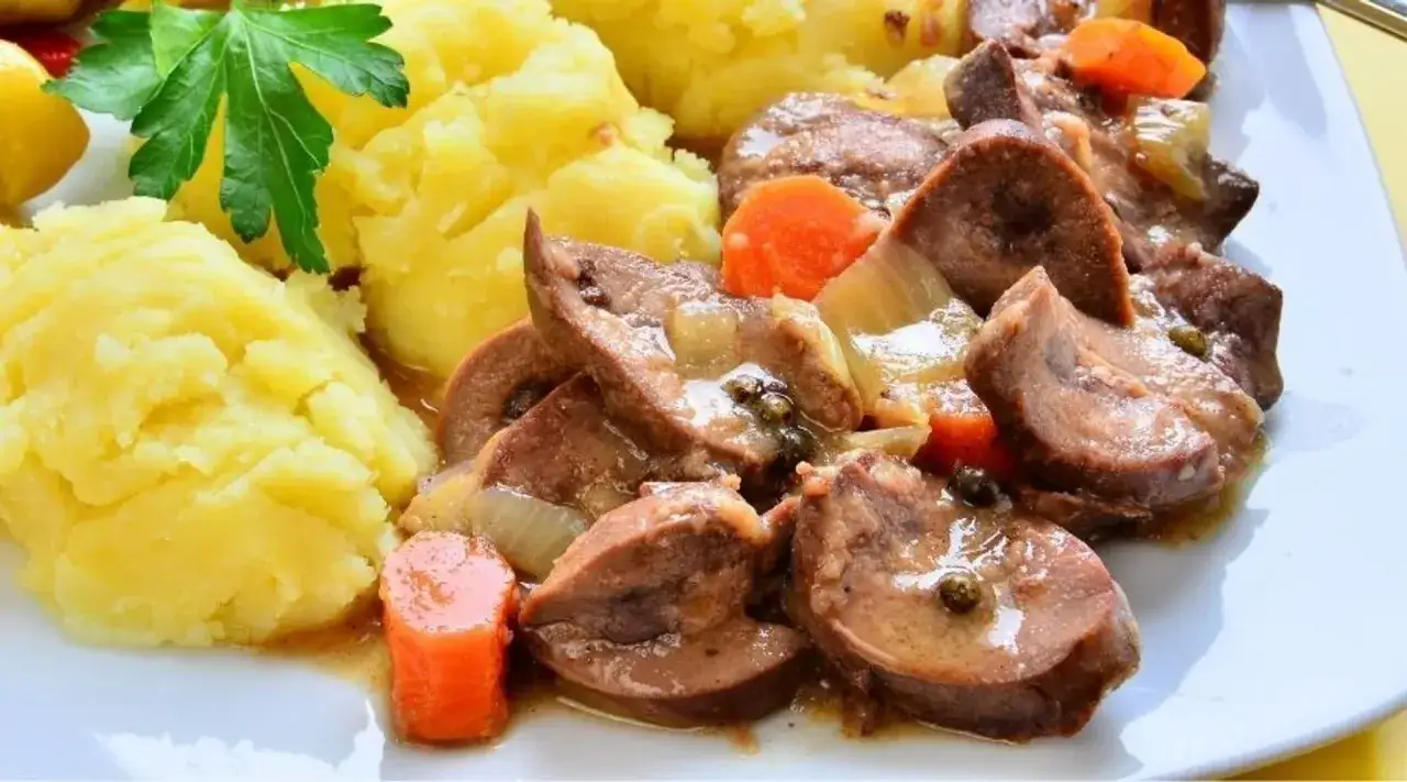 Grasica duszona z warzywami i pieczonymi ziemniakami, udekorowana natką pietruszki.
