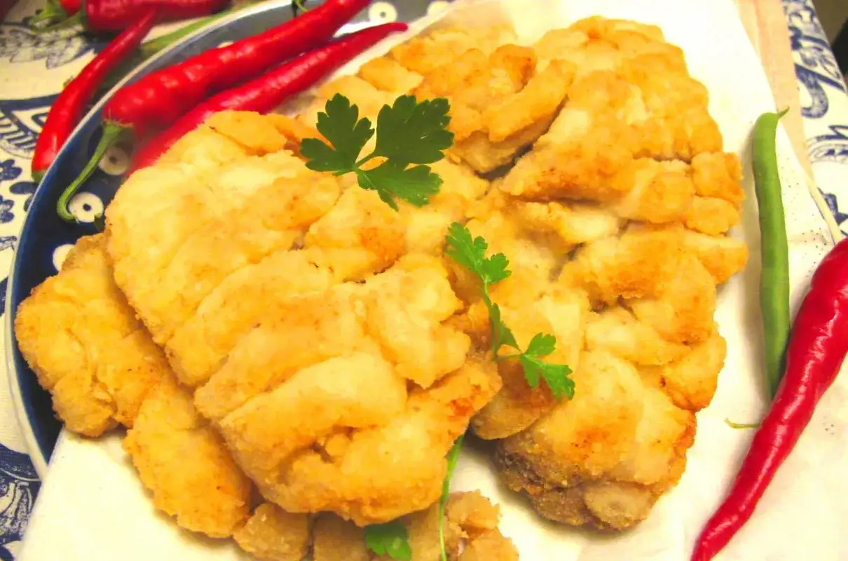 Chrupiący leszcz ryba w panierce, ozdobiony natką pietruszki, z papryczkami chili i fasolką szparagową.