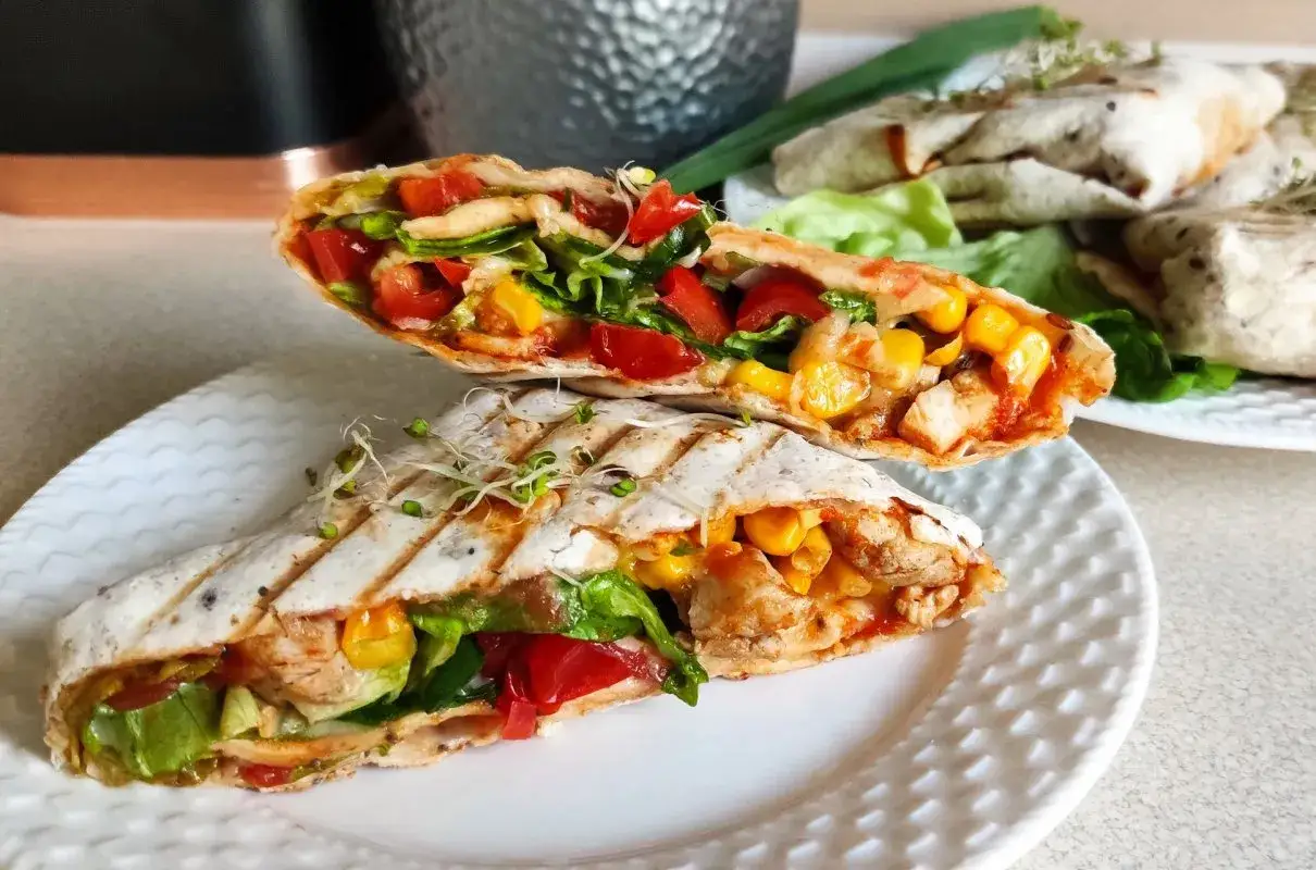Pyszna tortilla z kurczakiem na ciepło, pełna warzyw i kukurydzy, podana na talerzu.
