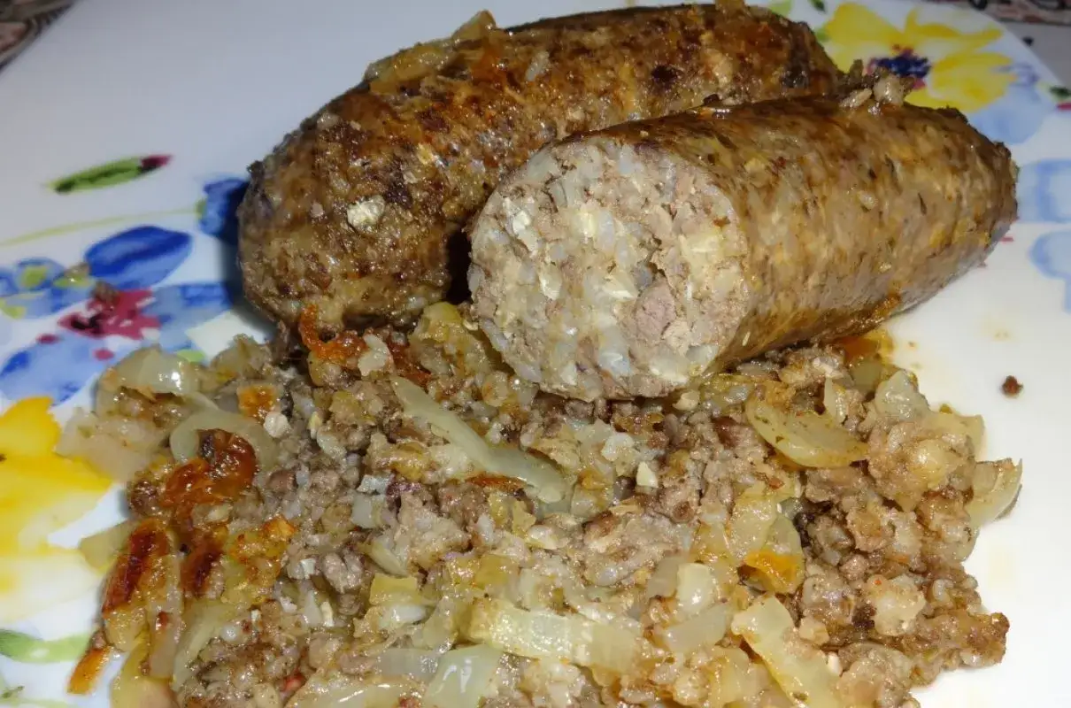 Dwie porcje białej kaszanki z cebulką na talerzu z kwiatowym wzorem.