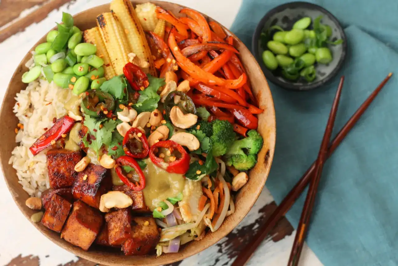 Kolorowa miska z ryżem, pieczonym tofu, edamame, brokułami, papryką i orzechami. Idealny szybki obiad z ryżem.