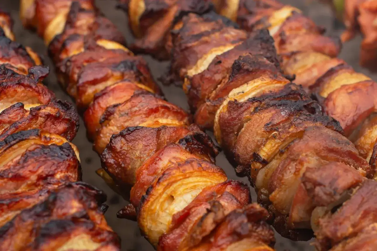 Szaszłyki z karkówki pieczone na grillu, apetycznie zarumienione, z widocznymi warstwami mięsa i tłuszczu.