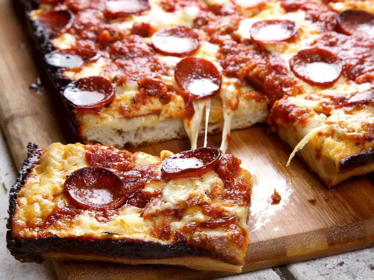 Pyszna detroit pizza z pepperoni, ciągnącym serem i chrupiącym spodem. Idealna na wspólne spotkanie.