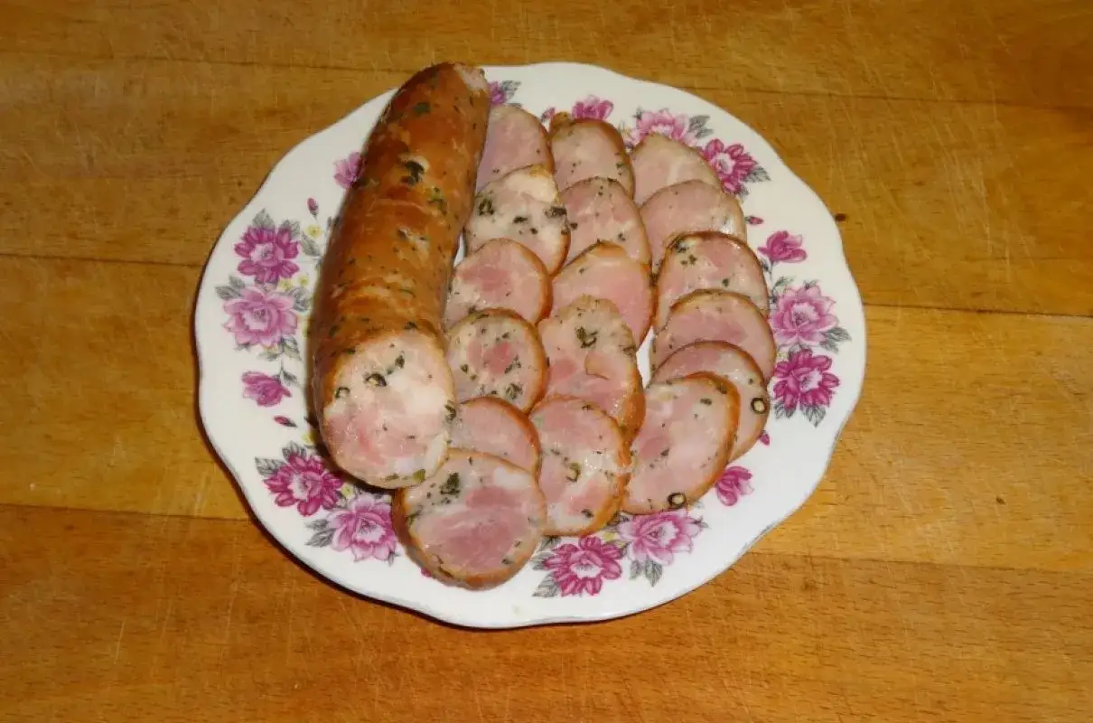 Kiełbasa drwala pokrojona na talerzu z kwiatowym wzorem. Idealna na grilla, oto jak zrobić kiełbasę drwala.